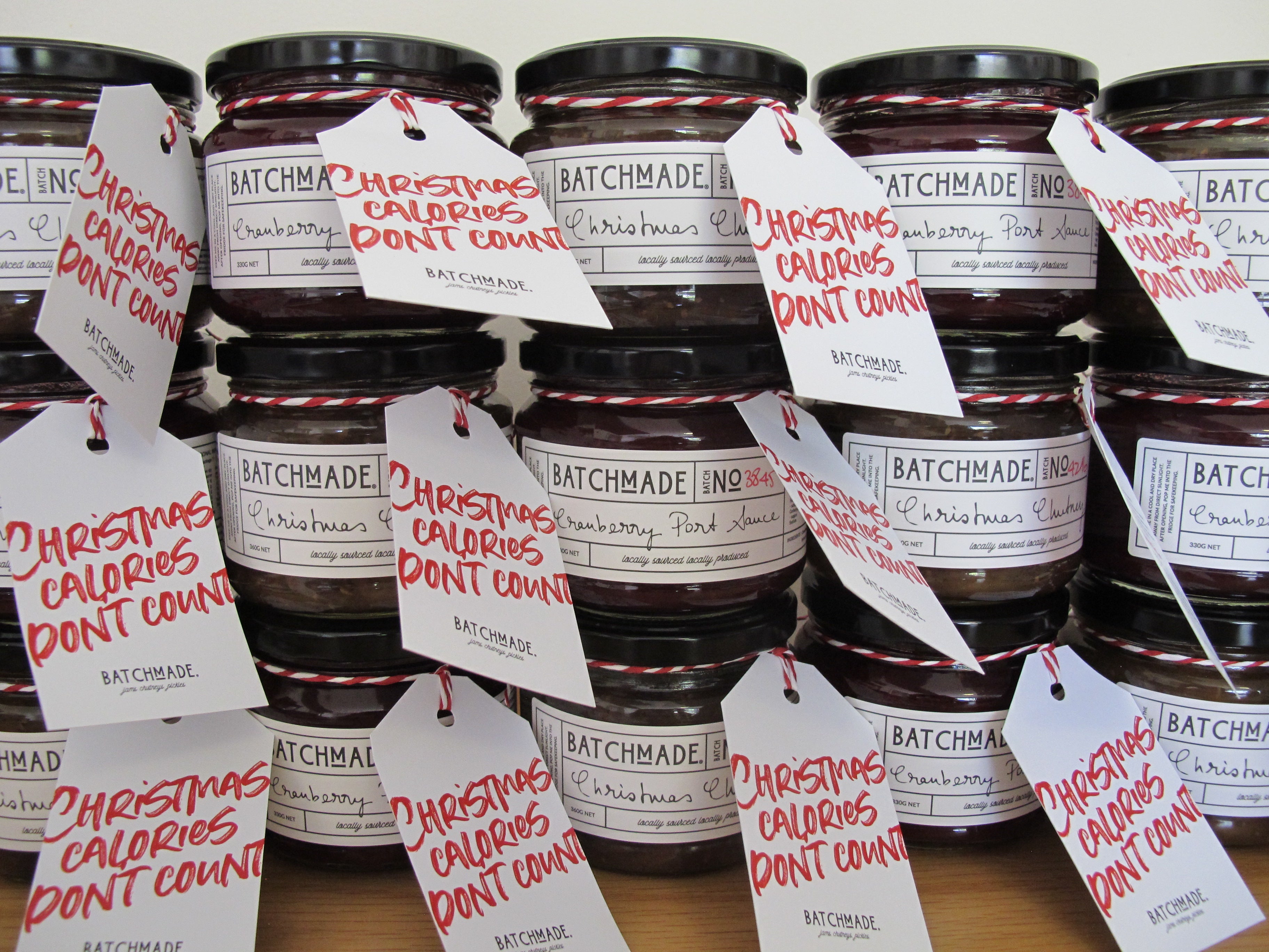 Wall of jars of BatchMade Christmas preserves each with  Christmas tag " Christmas calories don't count"