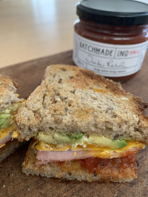 Toasted sandwich with avocado, egg, bacon and BatchMade tomato relish with jar of relish in background